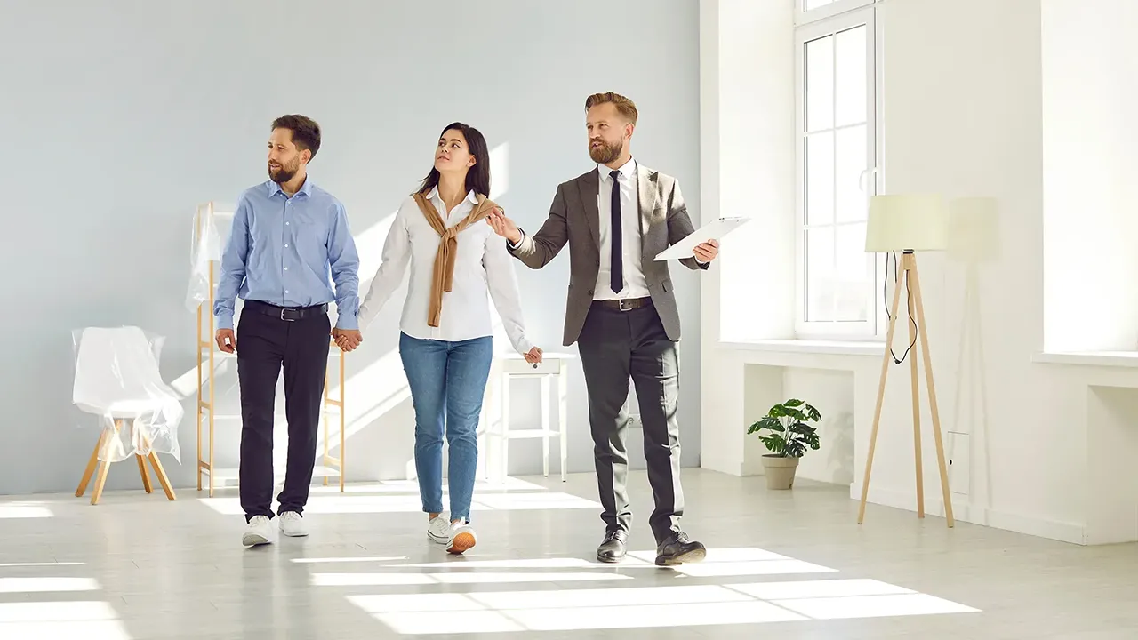 تصویر یک مشاور املاک که خانه ای را به خریداران نشان می‌دهد.